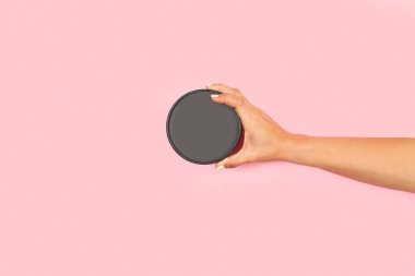 Pembe arka planda, fotokopi alanı olan yuvarlak bir karton kapağı tutan kadın.