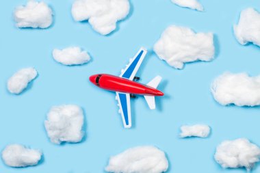 Bulutlar şekilli pamuk ve mavi arkaplan üzerinde oyuncak bir uçak