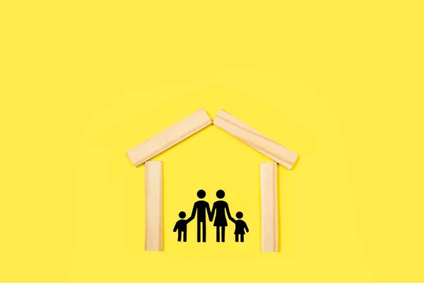黄色の背景に木製のブロックで作られた家の中に黒い紙で作られた家族 — ストック写真
