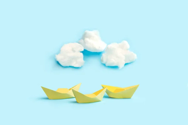 薄い青の背景に白い雲形の綿と黄色の紙のおもちゃのボート — ストック写真