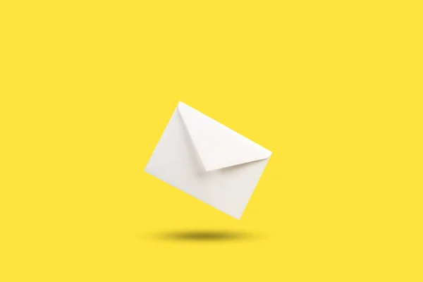 一个白色的信封漂浮在黄色的背景上 有复制的空间 — 图库照片