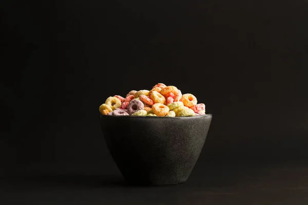 Frutta Sapore Cereali Colorati Una Ciotola Nera Uno Sfondo Nero — Foto Stock