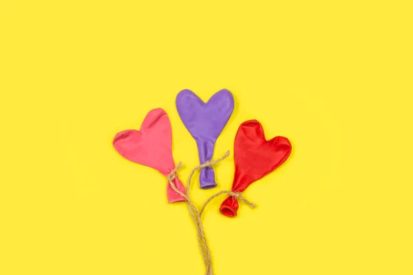 Heart Shape Deflated Colored Balloons Tied Sisal Thread Yellow Background — Stockfoto