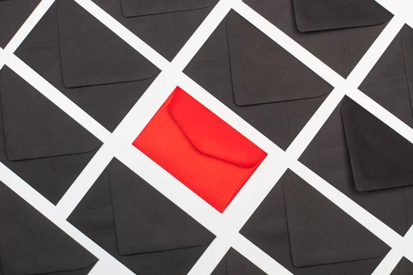 Black envelopes and one red on a white background in a top view