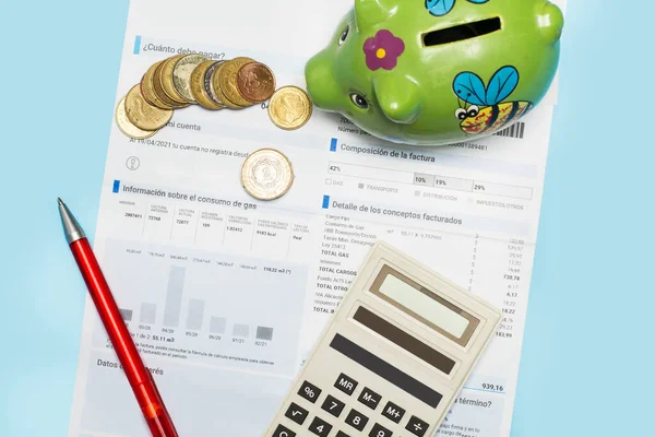 A gas invoice , coins and a calculator on a light blue background in a top view
