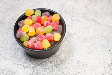 Colored gummies in a black bowl on a stone kitchen counter
