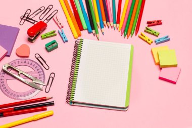 Blank open graph paper notebook and school utensils on a pink background with copy space