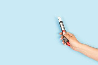 Açık mavi arkaplanda elinde siyah bir makas tutan bir kadın.