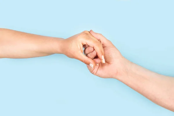 Man hand holding woman hand on a light blue background with copy space