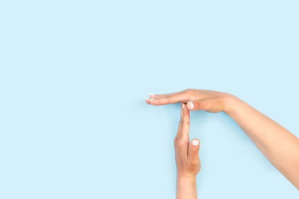 Woman hands doing time out gesture on a light blue background with copy space