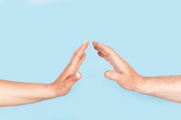 Woman and man hands doing stop gesture on a light blue background with copy space