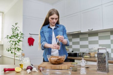 Genç kadın tavuk pişiriyor, baharatlarla marine ediliyor, evde, mutfakta karabiber tuzu var.