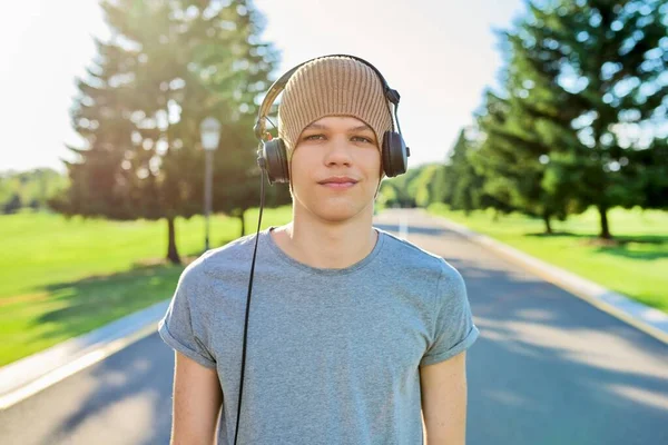 Retrato de hipster adolescente em chapéu de malha com fones de ouvido olhando na câmera — Fotografia de Stock