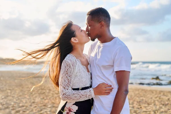 Amar romántico besos abrazando joven pareja multiétnica en la orilla del mar —  Fotos de Stock