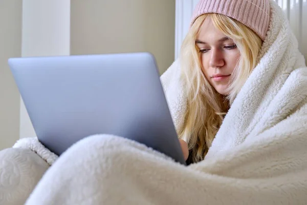 Teenager κατεψυγμένα κατά τη χειμερινή κρύα εποχή, ζέσταμα με καπέλο κουβέρτα, κοιτάζοντας φορητό υπολογιστή — Φωτογραφία Αρχείου