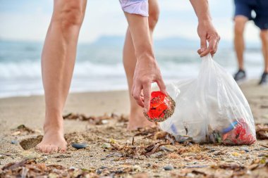 Plajda plastik çöpleri toplayan bir kadın elinin yakın çekimi. Çevre koruma, kirlilik, insanlar, doğa, ekoloji kavramı