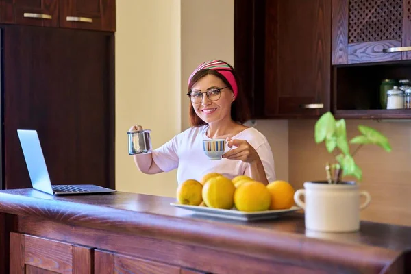Sonriente mujer relajante con café de la mañana con turk cezve y portátil en la cocina en casa — Foto de Stock