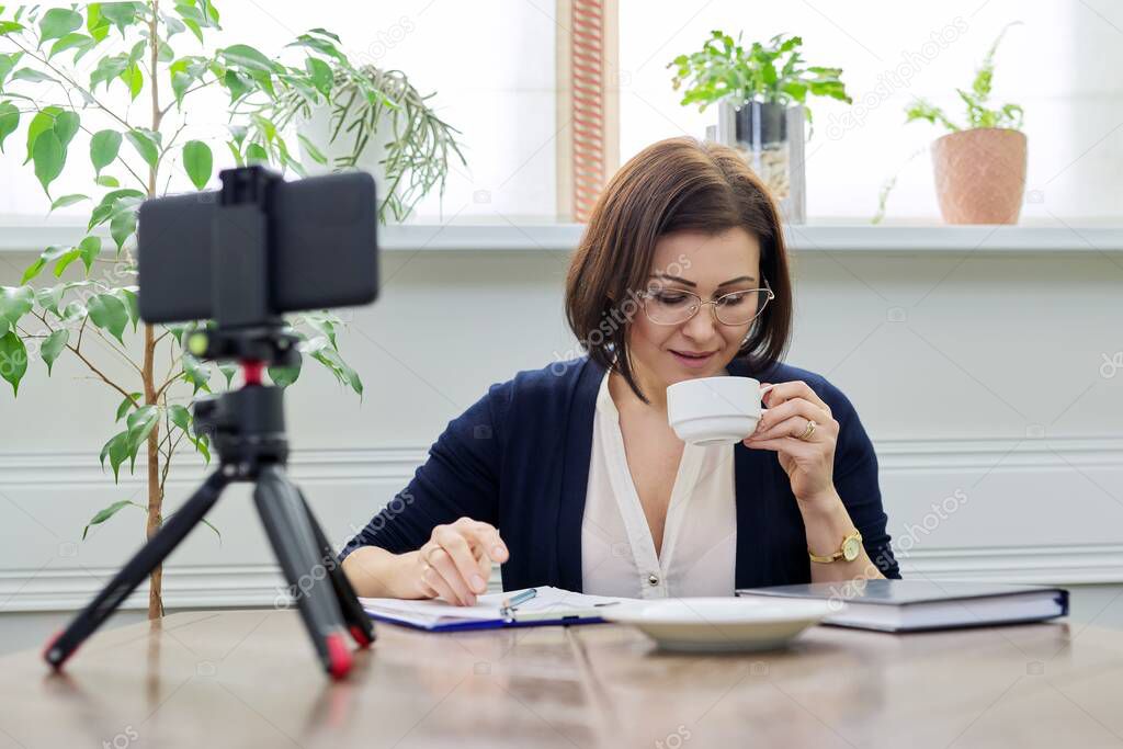 Middle aged business woman, counselor, mentor in a video meeting, using a smartphone