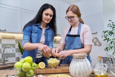Anne ve genç kız birlikte elmalı turta hazırlıyorlar.