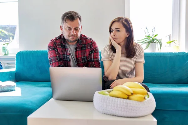 Serieuze middelbare leeftijd paar op zoek naar laptop scherm thuis in de woonkamer — Stockfoto