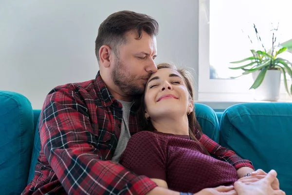 Felice coppia di mezza età che abbraccia a casa sul divano — Foto Stock