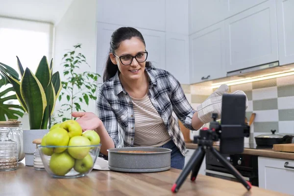 Vídeo de gravação feminina de uma receita de torta de maçã no smartphone em casa na cozinha — Fotografia de Stock