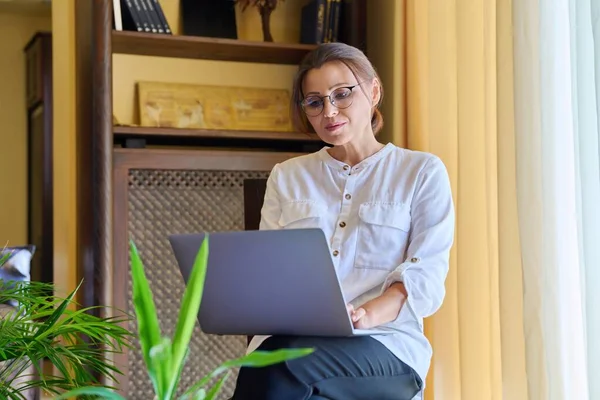 Vrouwenpsycholoog van middelbare leeftijd in een kantoor met een laptop. — Stockfoto