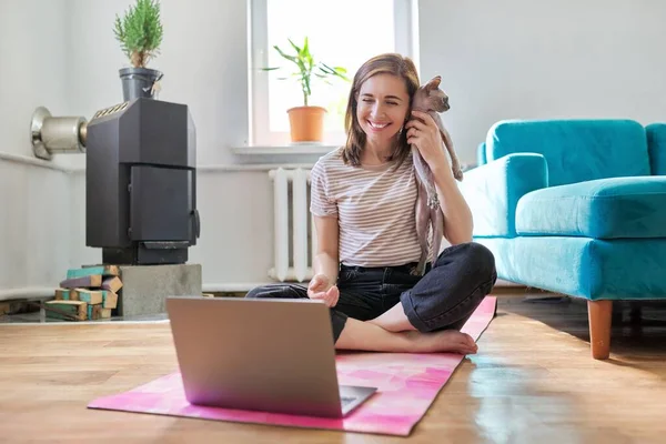 Usmívající se žena středního věku s laptopem a kočkou na podlaze — Stock fotografie