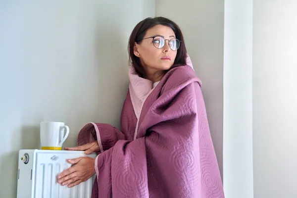 Koude winter herfst seizoen thuis, bevroren vrouw in de buurt verwarming radiator — Stockfoto