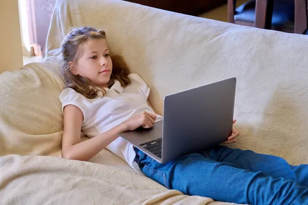 Bambino ragazza con computer portatile a casa sul divano — Foto Stock
