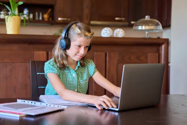 Ragazza pre-adolescente con laptop e cuffie studia a casa. — Foto Stock