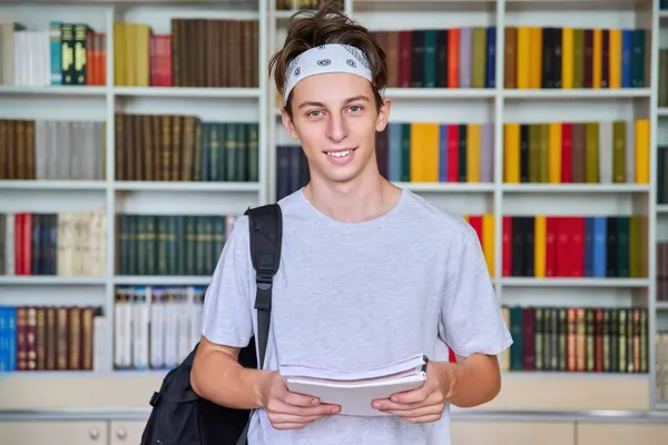 Porträtt av en manlig tonårsstudent som tittar in i kameran i biblioteket. — Stockfoto