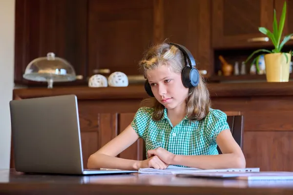 Ragazza pre-adolescente con laptop e cuffie studia a casa. — Foto Stock