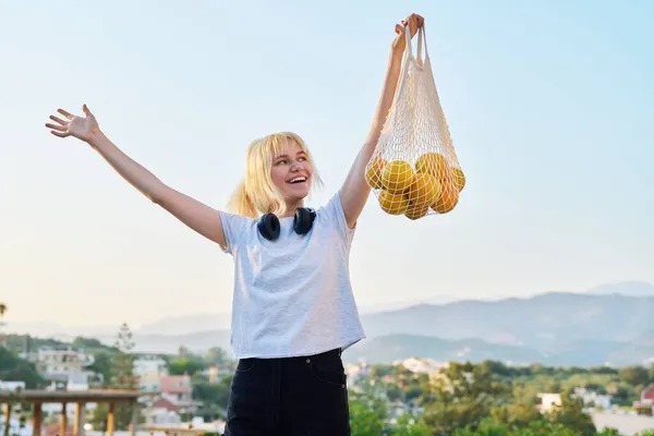 Una adolescente con una bolsa de malla ecológica de naranjas orgánicas de granja —  Fotos de Stock