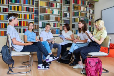 Kütüphanede orta yaşlı bayan öğretmeni olan bir grup genç.