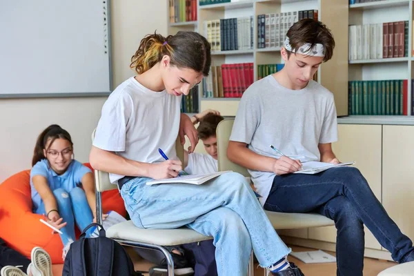 Un grupo de estudiantes adolescentes estudian juntos en la biblioteca. —  Fotos de Stock