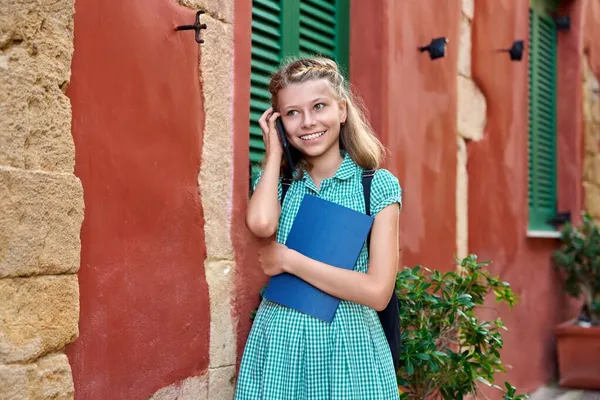 Malá holka student s batohem mluvit na smartphone venku — Stock fotografie