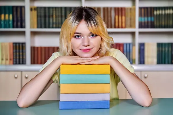 Adolescente lycéenne regardant la caméra avec des livres à la bibliothèque — Photo