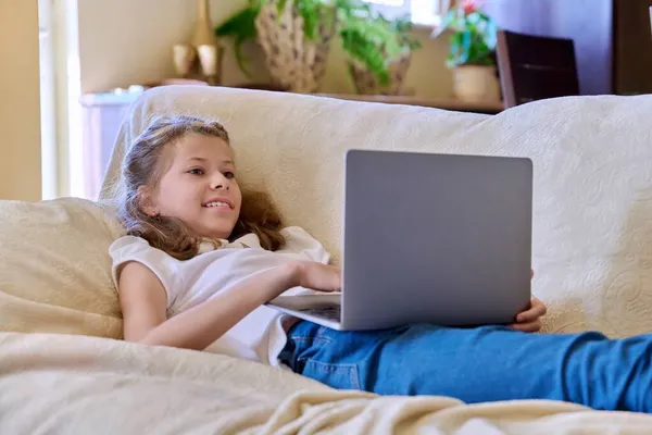 Child girl with laptop at home on the couch — Stock Photo, Image