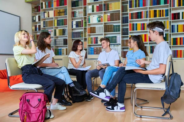 Groep tieners met middelbare leeftijd vrouwelijke leraar in de bibliotheek — Stockfoto