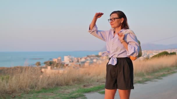 Donna di mezza età con borsa di arance fresche godendo la natura, tramonto, paesaggio marino — Video Stock