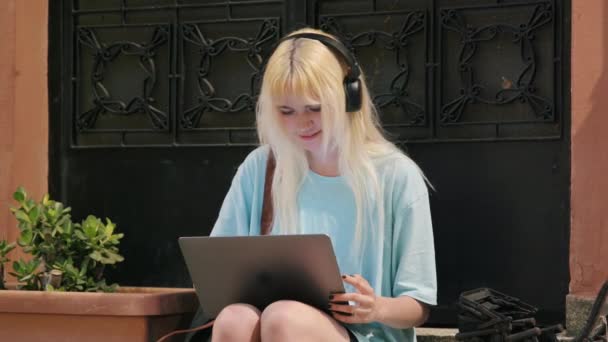 Estudante adolescente usando laptop, sentado nos degraus da casa na cidade da noite — Vídeo de Stock