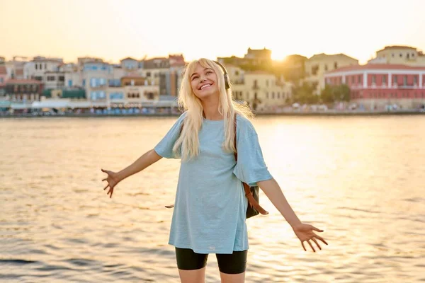 หญิงวัยรุ่นที่มีความสุขในหูฟังพร้อมกระเป๋าเป้สะพายหลังเพลิดเพลินกับการท่องเที่ยวในเมืองยุโรป ทะเล — ภาพถ่ายสต็อก