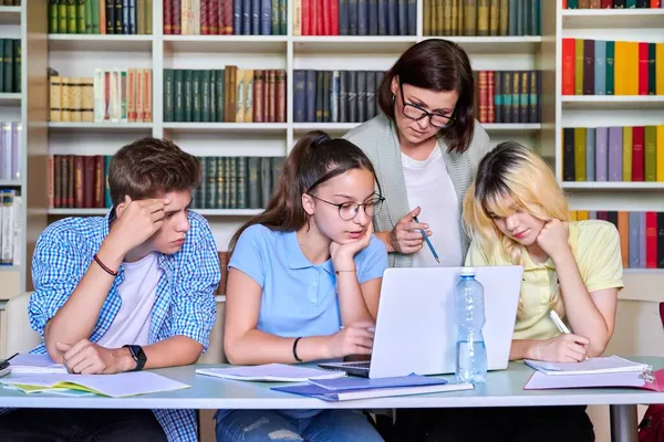 Lição em biblioteca, professora do ensino médio com grupo de adolescentes — Fotografia de Stock