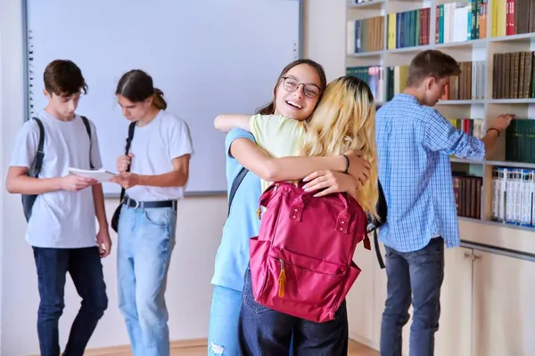 Estudiantes niñas abrazándose en la reunión, grupo de adolescentes en la biblioteca de la escuela —  Fotos de Stock