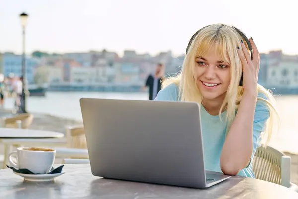 Sorridente bella ragazza adolescente in cuffia guardando in un computer portatile. — Foto Stock