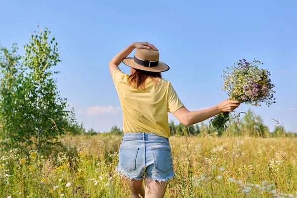 头戴草帽的女人带着野花跑在草地上，后视镜 — 图库照片
