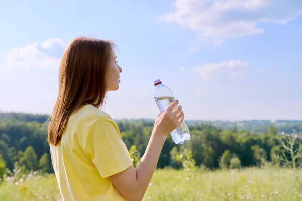 Gorące słoneczne lato, spragniona dorosła kobieta pijąca wodę z butelki do nas w naturze — Zdjęcie stockowe
