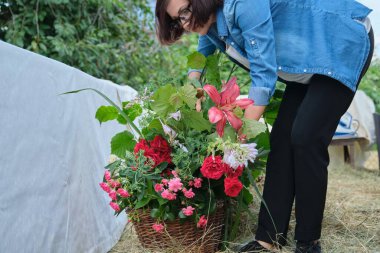 Kadın çiçekçi, açık havada çiçek düzenliyor. Çiçek sepeti oluşturma çalışma akışı