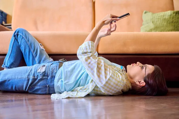 Reife Frau entspannt sich zu Hause mit Smartphone — Stockfoto